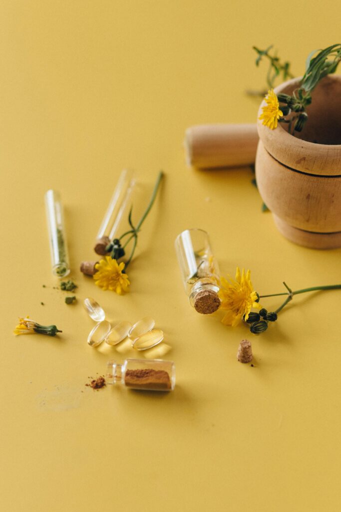 A still life of herbal remedies with yellow flowers and glass containers on a yellow background.